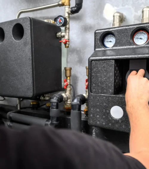 Modern electric boiler room in the house. Equipment for water heating system with automatic control unit. Close-up of a man's hand